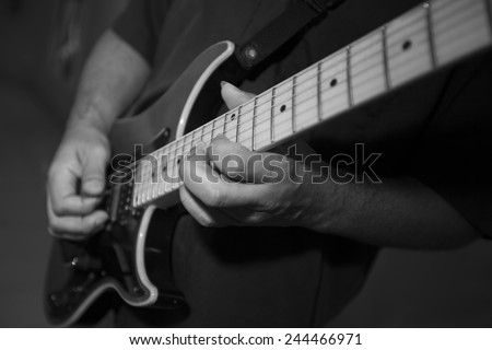 Black and white photo of hands playing electric guitar