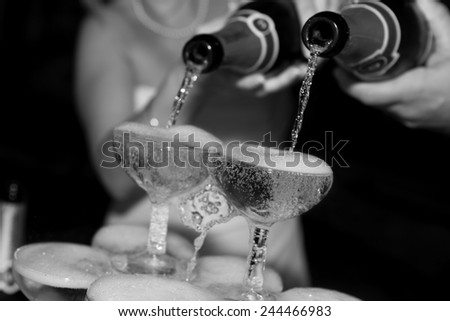 Black and white photo of champagne poured into a glass during wedding