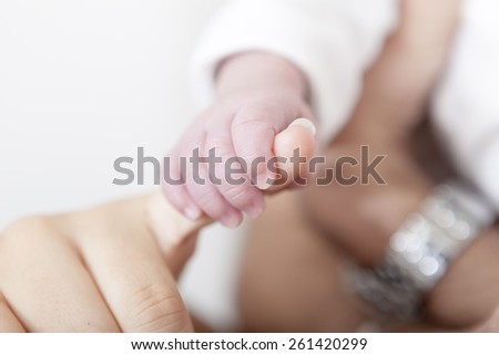 A baby\'s hand holding the finger of his dad or his mom with shallow depth of field
