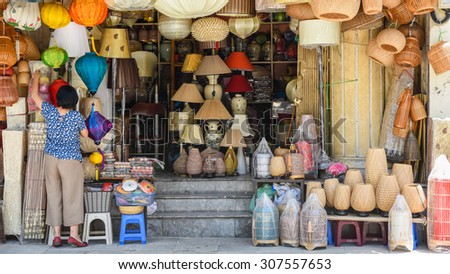 An unidentified woman is arranging handmade products in a shop. These products are made from bamboo and woven rattan on the sidewalk of Hang Trong street, Hanoi, Vietnam.
