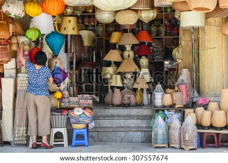An unidentified woman is arranging handmade products in a shop. These products are made from bamboo and woven rattan on the sidewalk of Hang Trong street, Hanoi, Vietnam.