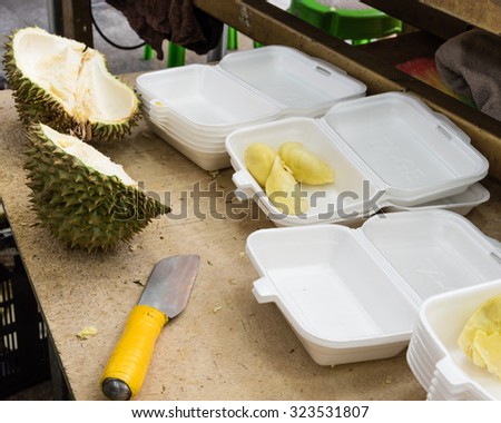 Peeled durian in pre-pack boxes, next to it is a knife, the tool to peel durian. Selective focus on the boxes, they are ready to sell as to-go, convenience fresh durian packs
