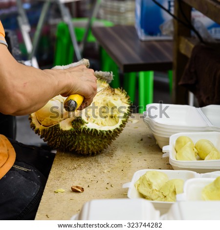 A fruits shop owner is using knife to peel durian in the wet market in Singapore. After peeling durian are packaged into fresh to-go, ready to eat, convenience packs and sell locally