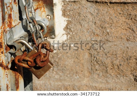 rusty chain and lock against a cement brick wall