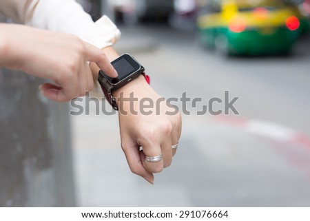 A female(woman) hand hold(touch) a smart watch on her left hand.