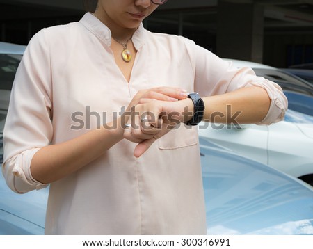 A female(woman) looking at her Smart Phone on her left hand. background car park