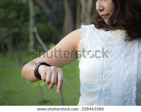 A female(woman) looking at her smart watch in park.