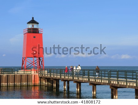 A lighthouse with a family walking towards it.  Focus on the lighthouse, with the family out of focus walking away from camera.