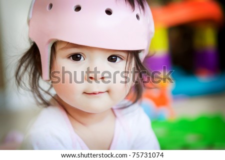 A baby girl with an orthopedic helmet smiles for the camera