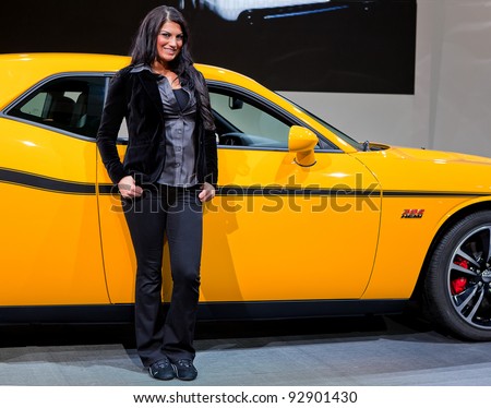 DETROIT - JANUARY 11: A model strikes a pose with the Dodge SRT Challenger at the 2012 North American International Auto Show Industry Preview on January 11, 2012 in Detroit, Michigan.