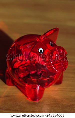 Red piggy bank with coins inside on a wooden table