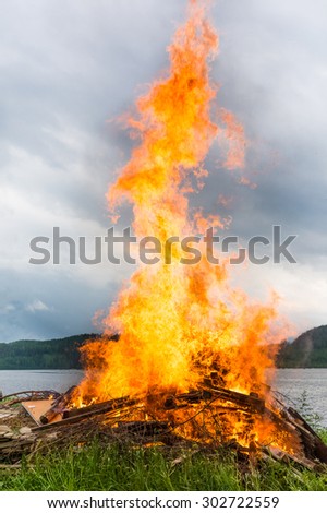 Midsummer bonfire on a lake beach.