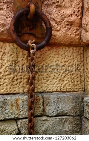 Chain and hook rusted on a stone wall