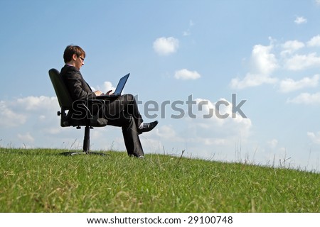 Businessman on office chair working with a laptop outdoor