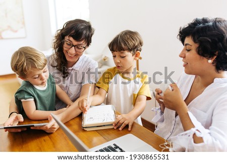 Happy LGBT family at home. Lesbian couple sitting with their kids using a digital tablet.