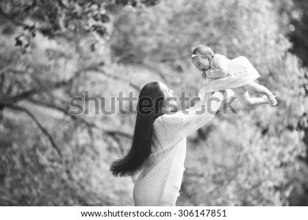 beautiful woman with long brown hair is playing with her baby girl daughter in the park black and white picture