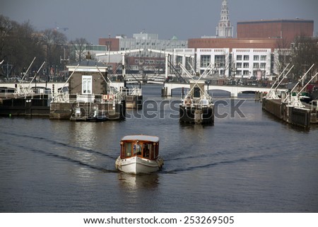 15 february 2015 Amsterdam , the Netherlands View at the river Amstel in amsterdam in the background you see the city hall and the skinny bridge.In front there is atour boat