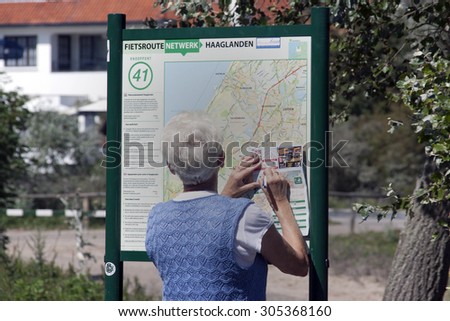 Hague ,Netherlands-August 6, 2015: Senior woman looking up the road bike at the bicycle network,A cycle network is a network of different routes via nodes are linked.