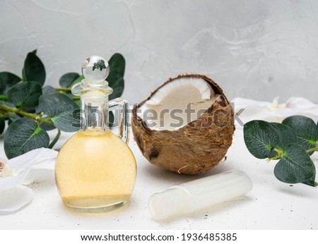 Coconut oil and coconut cream on a white table with green leaves. Coconut on a light background