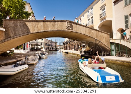 Port Grimaud, France - 22 June: People in the boat greet friends on the bridge in Port Grimaud, France