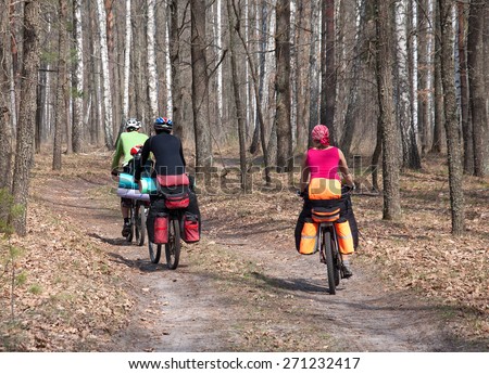 A group of tourists on a mountain bike ride on a forest trail. The rider is back