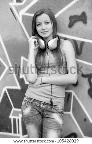 Style teen girl with sunglasses near graffiti background. Style teen girl near graffiti background. Photo in black and white style.