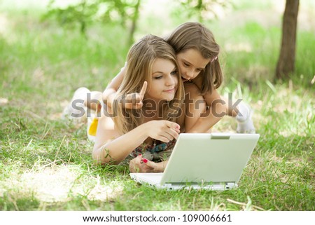 Two sisters with laptop in the park.