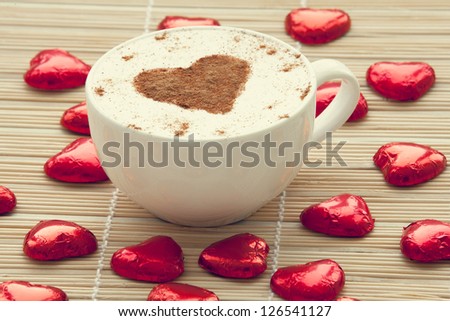 Cup of coffee with heart symbol and candy around.