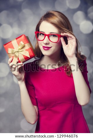 Redhead girl in dress with present box. Bokeh.