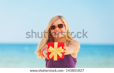 Blonde girl with gift at the beach.