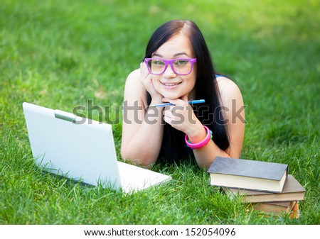 Teen girl with laptop in the park.