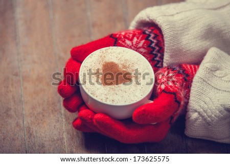 Hands in mittens holding hot cup of coffee. Photo in old color imagestyle.