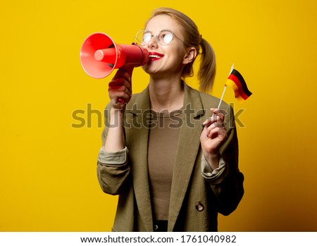 Style blonde woman in jacket with German flag and megaphone on yellow background Foto d'archivio © 