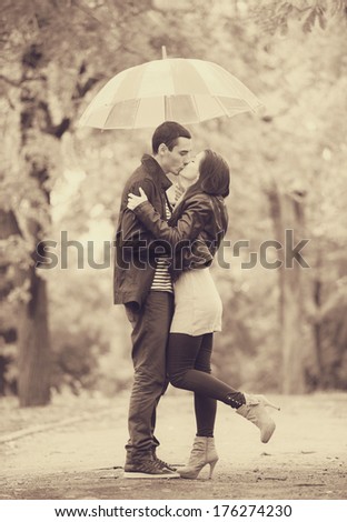 couple with umbrella kissing outdoor in the park. Photo in old color image style.