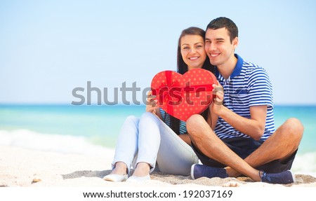 Young couple with gift on the beach in summer day.