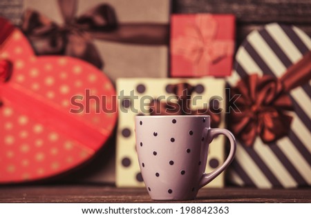 Cup of coffee and gifts on background.