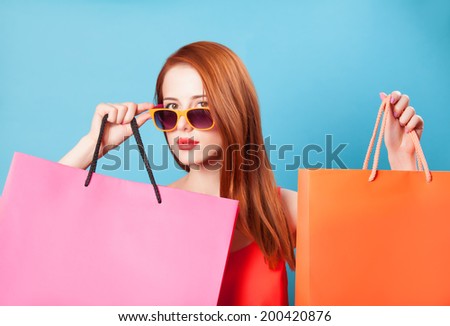 Style redhead women holding shopping bags on blue background.