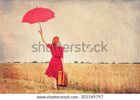 Redhead girl with umbrella and suitcase at outdoor
