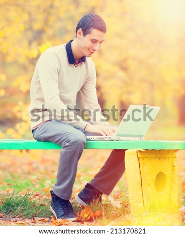 Programmer with notebook sitting in autumn park