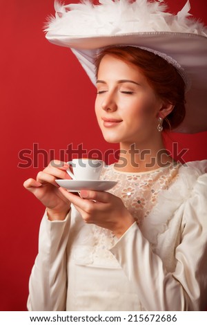 Portrait of redhead edwardian women with cup on red background.