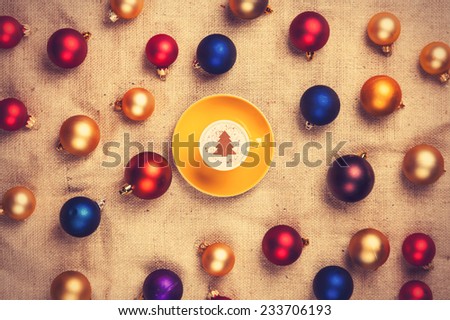 cappuccino with christmas tree shape and with red, blue and gold christmas balls on jute background.