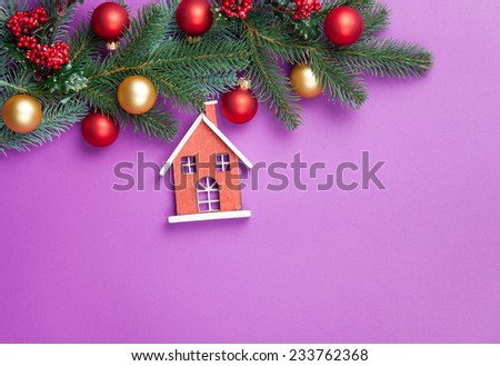 Toy house and pine branches with toys on violet background.