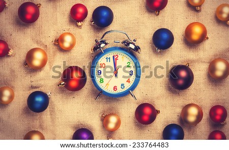 Retro alarm clock with gold, blue and red balls on jute background.
