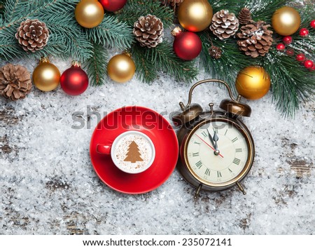 Cappuccino with christmas tree shape and clock on artificial snow background.