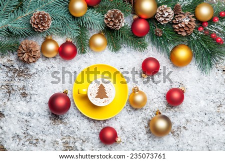 Cappuccino with christmas tree shape and pine branch on artificial background.