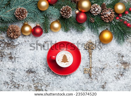 Cappuccino with christmas tree shape and key on artificial snow background