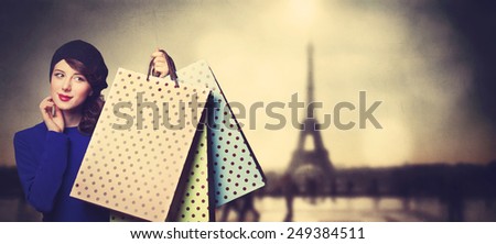 Portrait of beautiful women in blue dress with shopping bags on Parisian background.