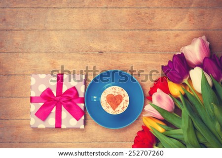 Cup of Cappuccino with heart shape symbol and gift box on wooden background