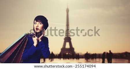 Surprised women in blue dress with shopping bags on parisian background.