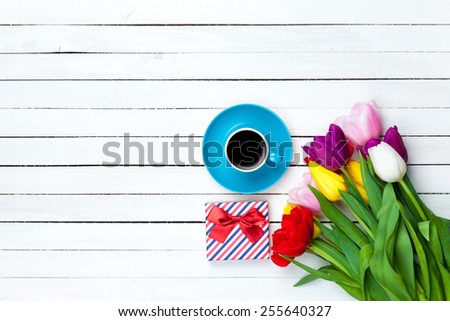 Cup of coffee and gift box on white wooden background
